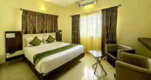 a bedroom with a bed and a couch and a chair at Daffodil Suites, Manyata Tech Park, Bengaluru in Bangalore