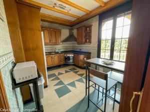a kitchen with wooden cabinets and a table and chairs at Casa Rural El Junquillo in Cuevas de San Marcos