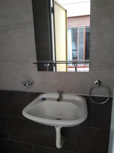 lavabo blanco en el baño con espejo en La Chicharra en Villa Carlos Paz