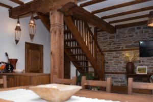 a dining room with wooden beams and a table and a tv at Къщата на музиканта in Leshten
