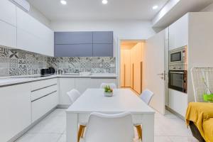 a white kitchen with a white table and chairs at Floriana Cozy Haven in Il-Furjana