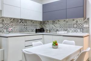 a white kitchen with a white table and chairs at Floriana Cozy Haven in Il-Furjana