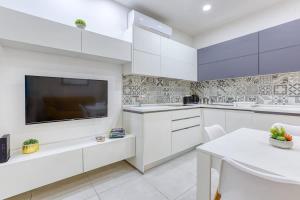 a kitchen with white cabinets and a flat screen tv at Floriana Cozy Haven in Il-Furjana +24 photos
