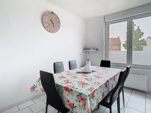 a dining room with a table with chairs and a clock at Le refuge de Gavrelle - Maison 6 lits, Wifi in Gavrelle