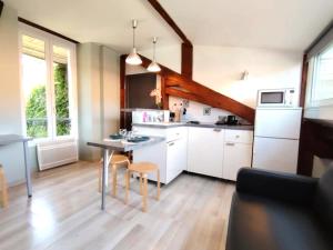 a kitchen with white cabinets and a table and chairs at Le studio du centre in Gap
