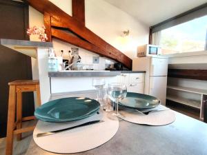 a table with two green plates and wine glasses at Le studio du centre in Gap +6 photos