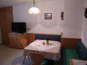 ein Zimmer mit einem Tisch und einem TV sowie einem kleinen Tisch mit einer Katze auf in der Unterkunft Apartments Penz in Zellberg