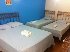 two beds in a room with blue walls at Pousada Praia da Costa in Vila Velha