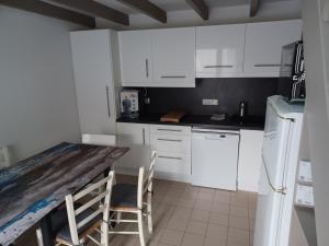 a kitchen with white cabinets and a wooden counter top at maison 100 m de la plage à pieds in Portiragnes +17 photos