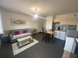 a living room and kitchen with a couch and a table at L'Héloïse, studio à Arras en résidence sécurisée in Arras