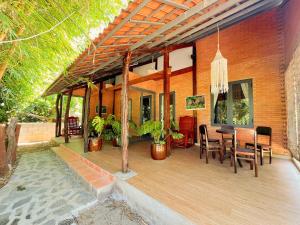a house with a wooden deck with a table and chairs at An Tiên Ecolodge in Tân Phú