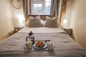 a bed with a tray of food on it with two cups at The Old Post Box in Holton