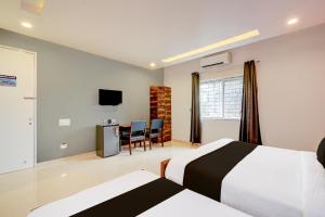 a bedroom with a bed and a desk and a tv at Super Hotel O SRI NIRVANA PLAZA in Gachibowli +22 photos