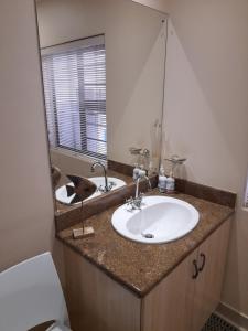 a bathroom with a sink and a mirror at Barnard Self Catering Apartments in St Francis Bay +34 photos
