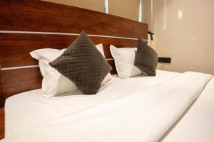 a bed with white sheets and pillows on it at Comfy GK Residency in New Delhi