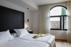a bedroom with two white beds and a window at Hotel Fernando III in Seville