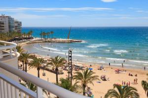 a view of a beach with palm trees and the ocean at UHC SANTILLANA FAMILY COMPLEX in Salou