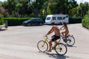 a man and a woman riding bikes in a parking lot at Camping Villaggio Il Pilone in Rosa Marina