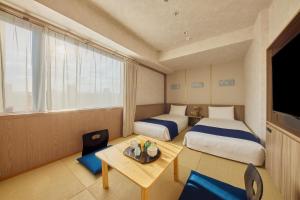 a hotel room with two beds and a table at Village Kyoto close by Shijo Omiya station in Kyoto