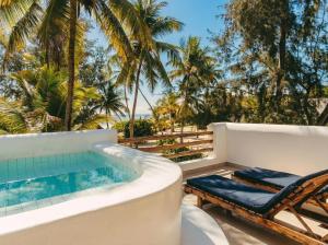 a resort pool with a chaise lounge and palm trees at Kijani Beach Villas in Bwejuu +108 photos