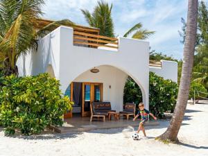 a young boy playing with a soccer ball in front of a house at Kijani Beach Villas in Bwejuu
