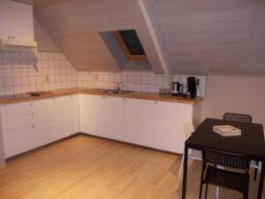 une cuisine avec des placards blancs et une table dans l'établissement Het Zolderhuis, à Arendonk