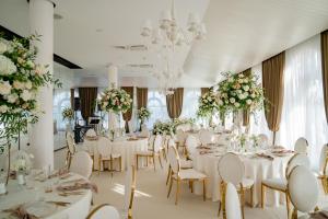 a banquet hall with white tables and chairs and flowers at Lighthouse Golf & Spa Hotel - Mineral Pools, Premium All Inclusive, SPA & Beach Access, Free Parking in Balchik +225 photos