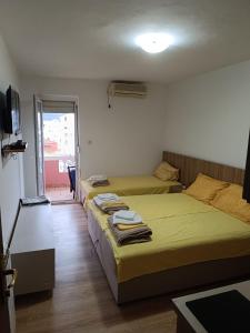 a bedroom with two beds and a tv and a window at Una Apartments in Budva