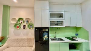 a kitchen with white cabinets and a black refrigerator at Vinsmart City Cam Cam homestay in Phú Thú