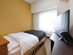 a small bedroom with a bed and a window at APA Hotel Gifu Hashima Ekimae in Hashima +37 photos