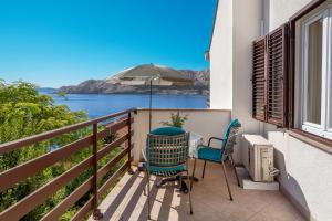 a balcony with a table and chairs and an umbrella at Double Rooms Jasna with Sea View in Baška +13 photos