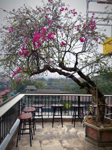 a tree with pink flowers on a balcony with stools at Hiden An Hotel in Ninh Binh