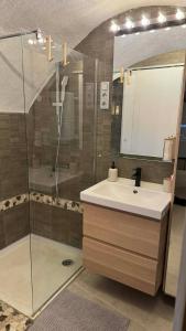 a bathroom with a sink and a shower with a mirror at Les Voûtes Secrètes - Love Room avec Balnéo à Bras in Bras +13 photos