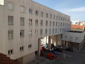 a large building with cars parked in a parking lot at Residencial Moeda in Coimbra