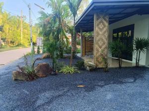 a building with trees and rocks in front of it at Lanta Maikaew Guesthouse in Ko Klang