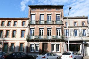 a tall brick building with cars parked in front of it at Le Beaulieu - Confort & espace avec climatisation - T4 central in Villefranche-de-Lauragais