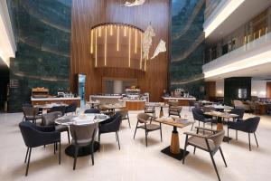 a restaurant with tables and chairs and a chandelier at Park Dedeman Konya in Konya