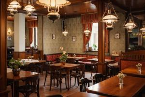 a restaurant with wooden tables and chairs and chandeliers at Stara šola Kaval in Novo Mesto