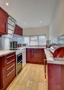 a large kitchen with red cabinets and wooden floors at 3 Bed in Croyde oc-yellow in Croyde +15 photos