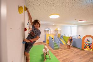 a young boy standing in a play room with a play area at Camping Seehof in Kramsach