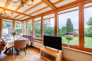 a dining room with a table with a tv and windows at 4 Bed in Satterthwaite oc-c32334 in Grizedale