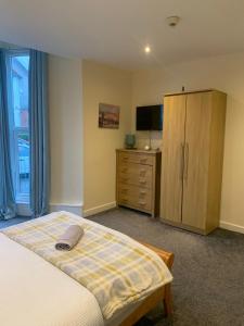 a bedroom with a bed and a dresser and a television at 36 flat 1 - Room 1 in Swansea