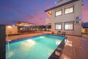 a swimming pool in front of a house at Vrundavan Villa Lonavala in Malavli