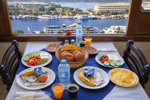 a table with plates of food and a view of a harbor at Hapi Hotel in Aswan