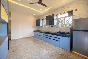 a large kitchen with blue cabinets and a ceiling fan at Vrundavan Villa Lonavala in Malavli