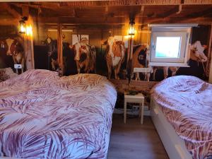 a bedroom with two beds and fake cows on the wall at B&B Verwoldsehof 'Op de deel' in Laren