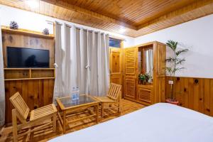 a bedroom with a table and chairs and a television at Manali Parvat View in Jagatsukh +9 photos