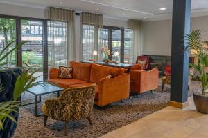 a lobby with orange couches and chairs at Hampshire Court Hotel & Spa in Basingstoke