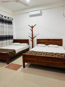 two beds sitting in a room with at Nimjaya holiday bunglow in Anuradhapura
