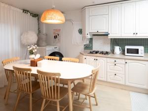 a kitchen with white cabinets and a table and chairs at Bandal Stay in Daegu in Daegu